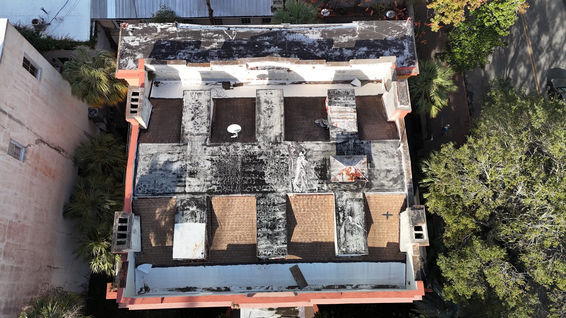 Top-down drone survey of an aging low-slope commercial roof showing ponding and patched areas